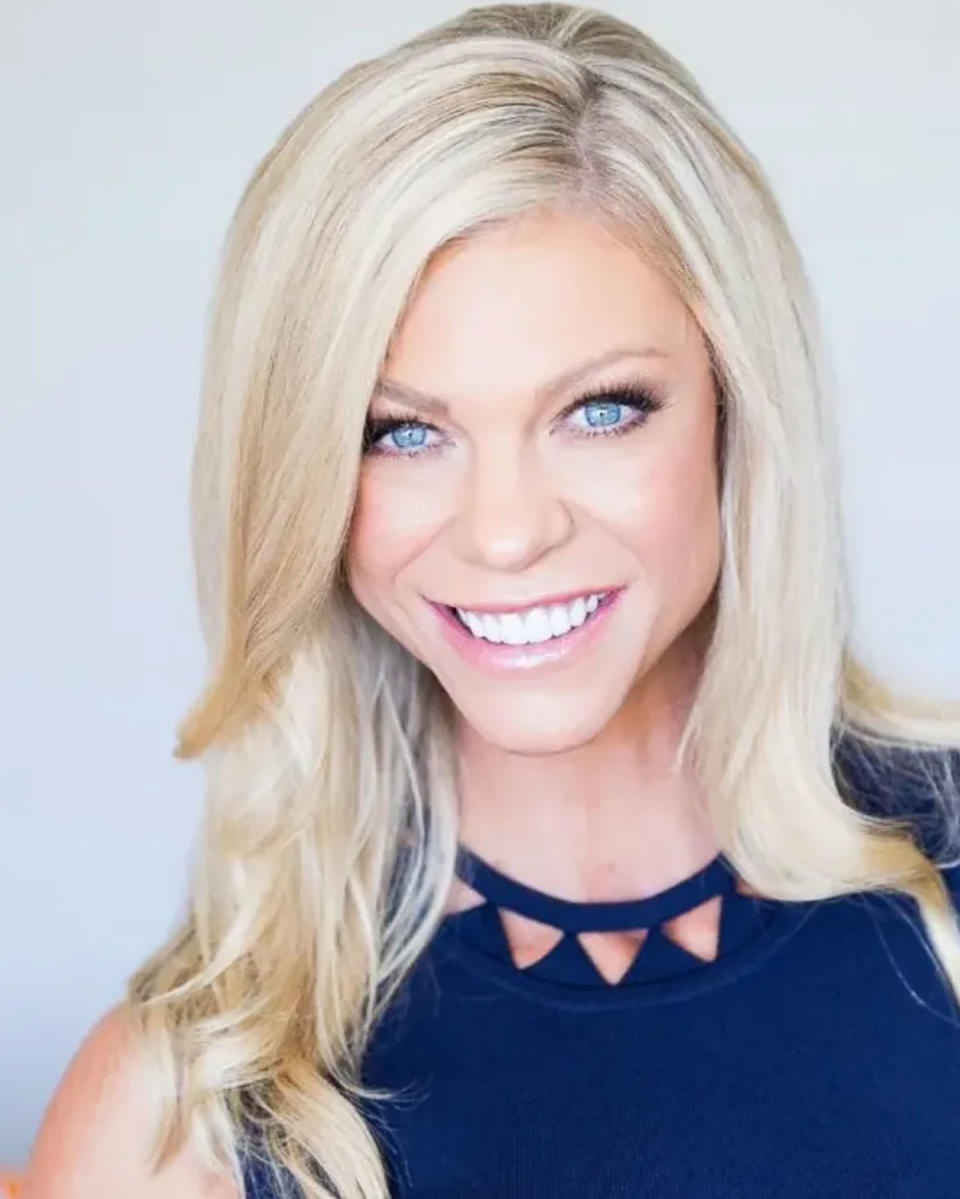 Erin Jayne Plummer smiling for the camera, wearing a navy blue top and her hair out.