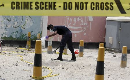 An explosives specialist police officer collects samples after a bomb blast in the village of Sitra, south of Manama, Bahrain, July 28, 2015. REUTERS/Hamad I Mohammed