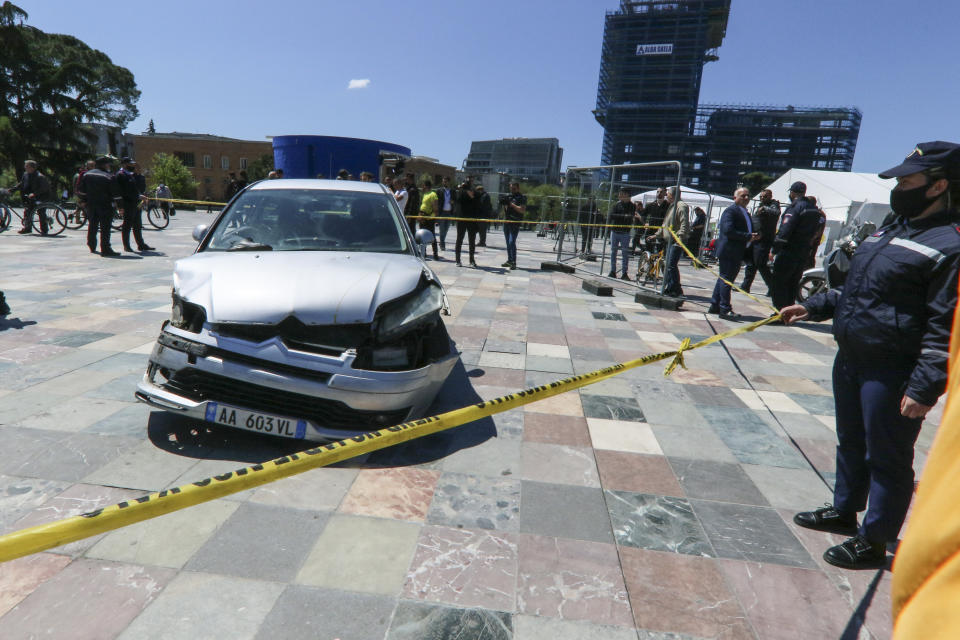 A police officer stands near to a damaged car on central Skanderbeg square, after an incident, in Tirana, Sunday, April 25, 2021. A man drove his car into the Albanian capital Tirana’s main square where vehicles are not allowed, the local media and police reported on Sunday. The driver broke the barriers to enter the Skanderbeg Square. A young man managed to stop the driver entering from the window. Then people dragged him out of the car. No one was injured. The car stopped near two big tents where people get vaccines and a smaller tent raised from the Syri Televizion private channel to cover the voting. (AP Photo/Hektor Pustina)