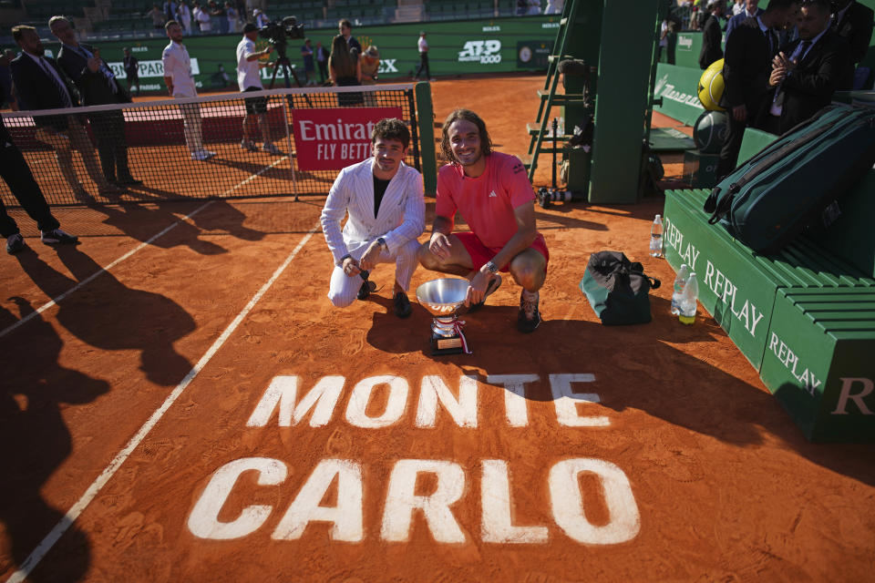 Stefanos Tsitsipas of Greece poses with the trophy alongside Ferarri F1 driver Charles Leclerc, left, after defeating Casper Ruud of Norway to win the Monte Carlo Tennis Masters final match 6-1, 6-4 in Monaco, Sunday, April 14, 2024. (AP Photo/Daniel Cole)