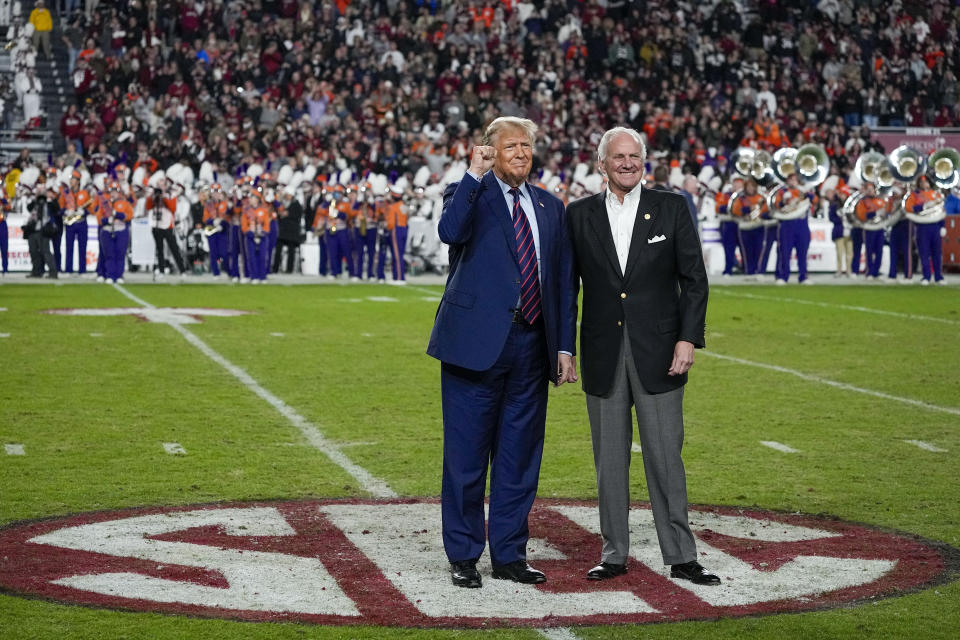 Republican presidential candidate and former President Donald Trump gestures with South Carolina Gov. Henry McMaster during halftime in an NCAA college football game between the University of South Carolina and Clemson Saturday, Nov. 25, 2023, in Columbia, S.C. (AP Photo/Chris Carlson)