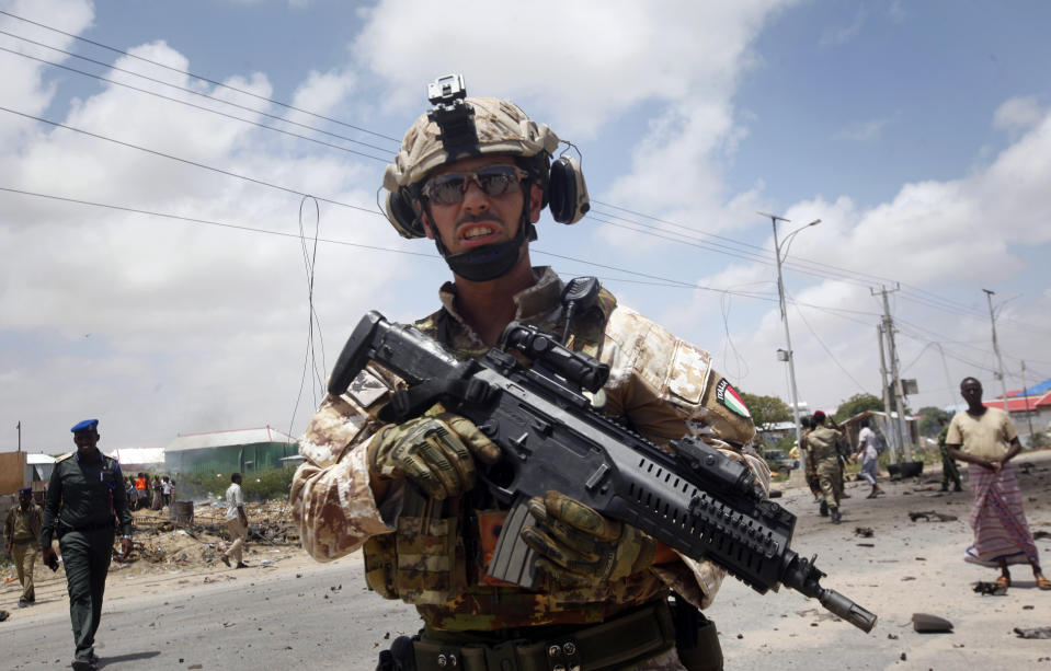 A member of the Italian military attends the scene after an attack on a European Union military convoy in the capital Mogadishu, Somalia Monday, Oct. 1, 2018. A Somali police officer says a suicide car bomber has targeted a European Union military convoy carrying Italian military trainers in the Somali capital Monday. (AP Photo/Farah Abdi Warsameh)