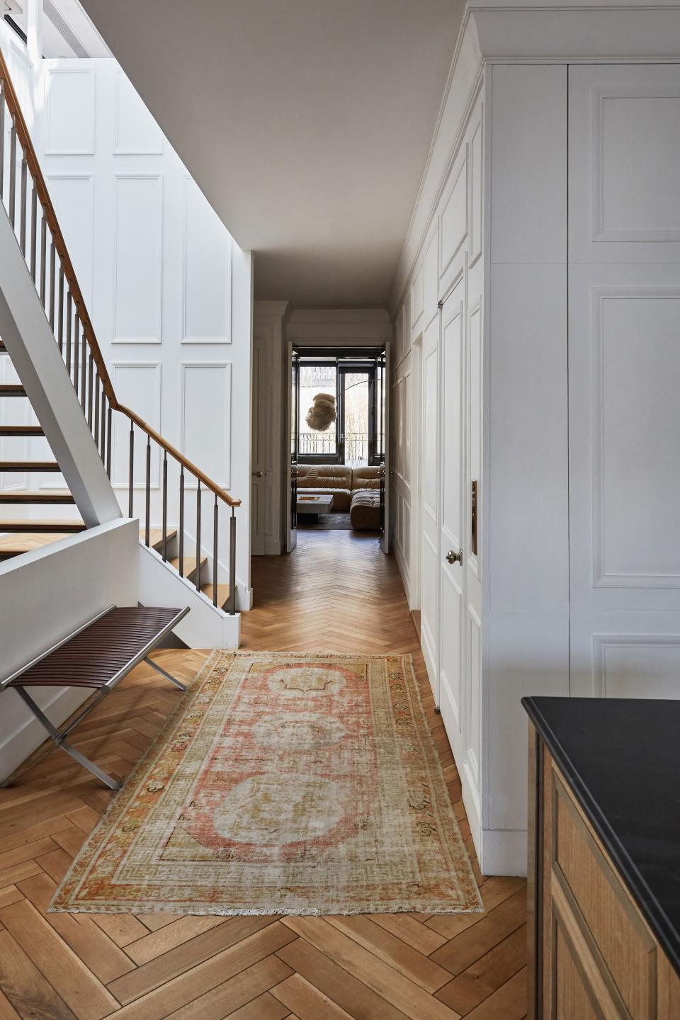 Blinken removed the existing carpeting and replaced it with herringbone floors. The rug seen here came from an auction at Bonhams. At the end of the hall is the library.