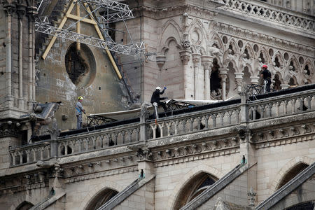 Workers install temporary tarpaulins to protect Notre-Dame Cathedral from rain damage, a week after a massive fire devastated large parts of the gothic structure in Paris, France, April 23, 2019. REUTERS/Benoit Tessier