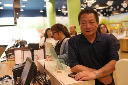 Lin Guo-cing, a senior official of the Chinese Unity Promotion Party, sits at a cashier at a theme park that he is planning to introduce to the China market, in Chiayi