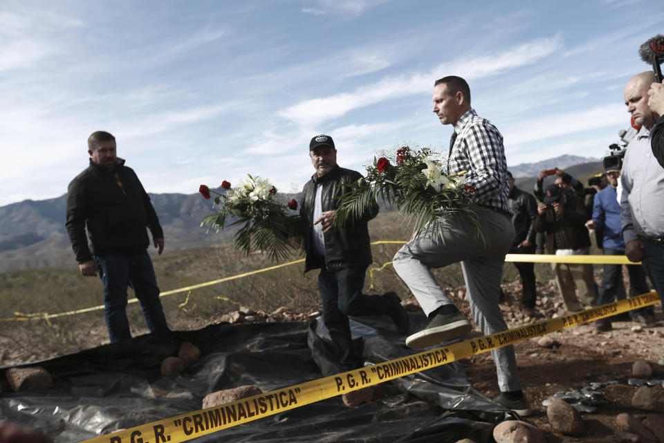 Bryan Lebaron, second from right, and relatives place flowers where one of the cars belonging to the extended LeBaron family was ambushed by gunmen last year near Bavispe, Sonora state, Mexico, Sunday Jan. 12, 2020. Lopez Obrador said Sunday there is an agreement to establish a monument will be put up to memorialize nine U.S.-Mexican dual citizens ambushed and slain last year by drug gang assassins along a remote road near New Mexico. (AP Photo/Christian Chavez)