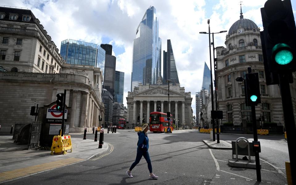 A woman passes the Bank of England in the financial district in the City of London - NEIL HALL/EPA-EFE/Shutterstock 