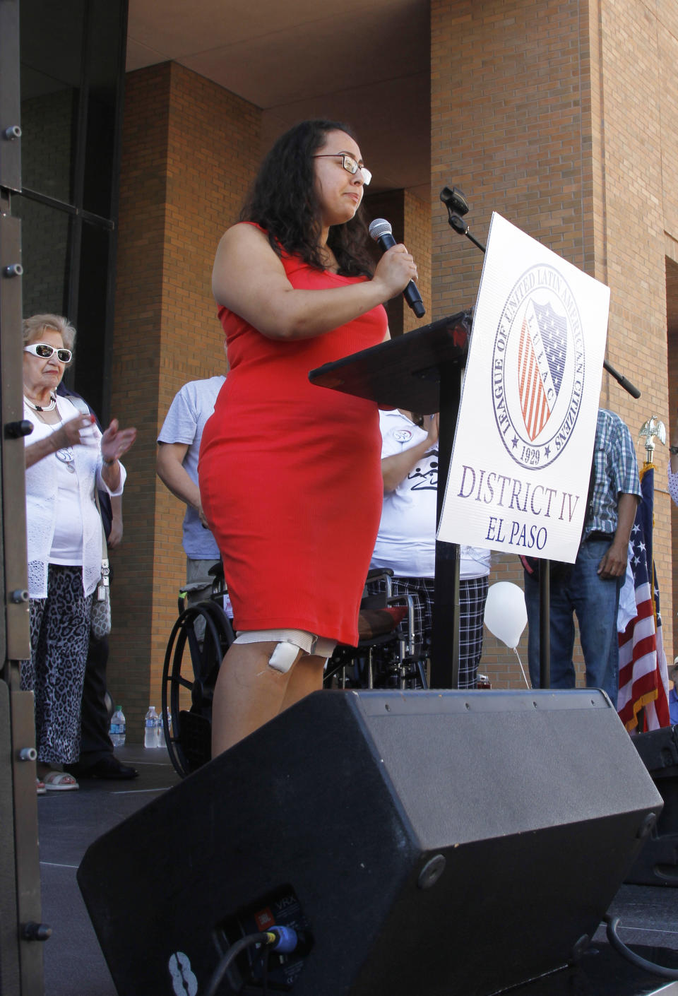 Jessica Coca Garcia stands in front of her wheelchair addressing those gathered at the League of United Latin American Citizens' "March for a United America" Saturday, Aug. 10, 2019 in El Paso, Texas. More than 100 people marched through the Texas border denouncing racism and calling for stronger gun laws one week after several people were killed in a mass shooting that authorities say was carried out by a man targeting Mexicans. Garcia and her husband were injured during the mass shooting. (AP Photo/Cedar Attanasio)