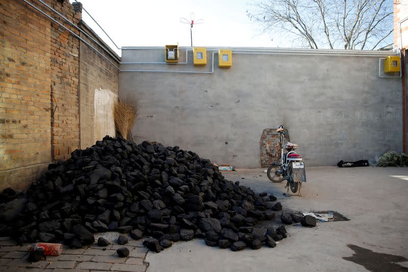FILE PHOTO: A pile of coal is seen underneath newly installed gas pipes in a courtyard in the village of Heqiaoxiang