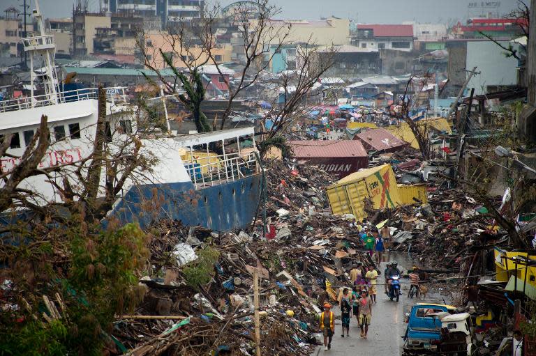 Displaced residents walk past a ship washed ashore by Super Typhoon Haiyan in Tacloban on November 23, 2013