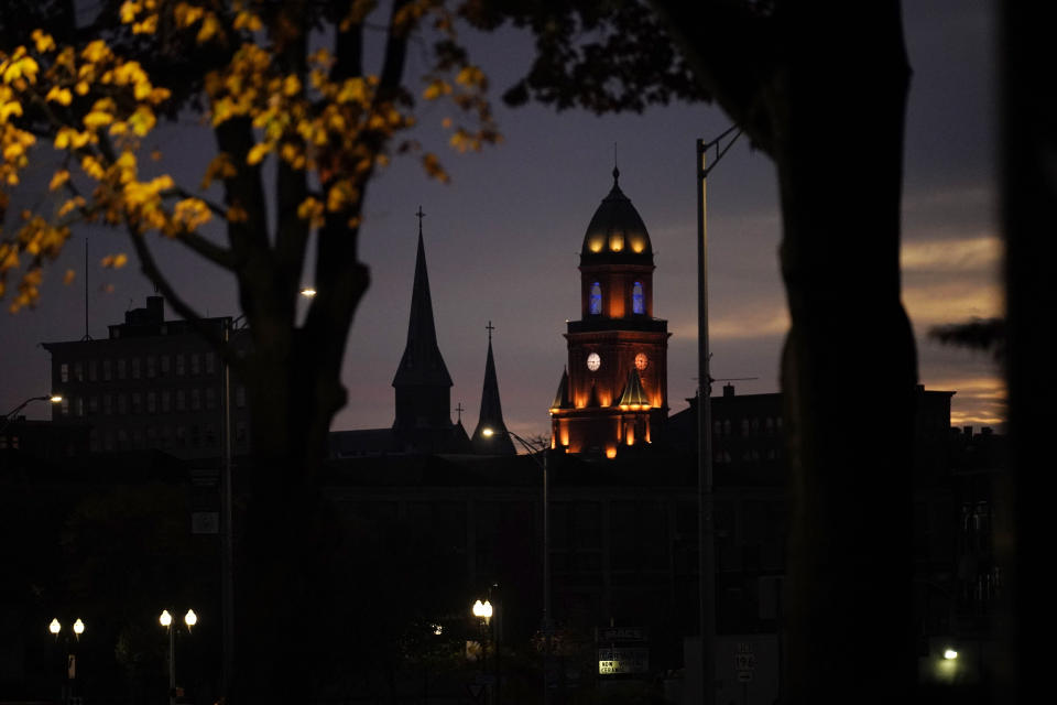 City Hall tower and church steeples are seen at dawn in Lewiston, Maine is seen at dawn, Thursday, Oct. 26, 2023. Residents have been ordered to shelter in place as police continue to search for the suspect of Wednesday's mass shooting at a local bar. (AP Photo/Robert F. Bukaty)