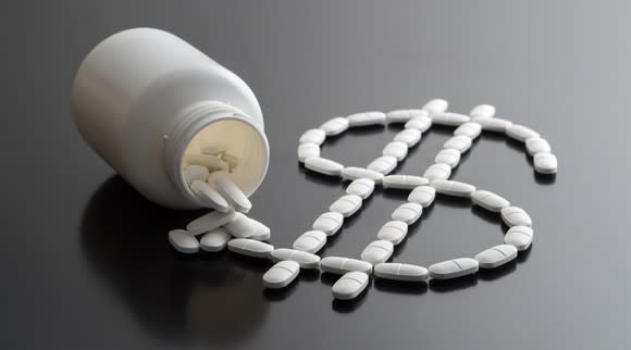 Pills spilling out of a prescription bottle form the shape of a dollar sign.