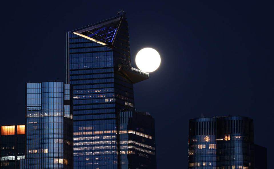 a bright full moon behind a skyscraper