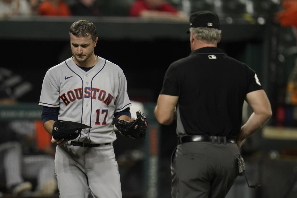 Houston Astros starting pitcher Jake Odorizzi, left, holds his hat and glove to present to first base umpire Ted Barrett for inspection during the fourth inning of a baseball game against the Baltimore Orioles, Monday, June 21, 2021, in Baltimore. (AP Photo/Julio Cortez)