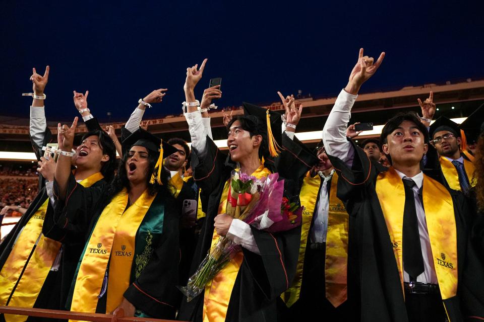 University of Texas graduates give the “Hook ’em, Horns” sign during Saturday night's commencement ceremony at Royal-Memorial Stadium. About 10,000 graduates attended.