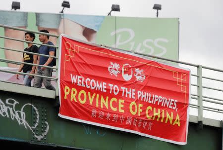 Residents walk past a banner reading "Welcome to the Philippines, Province of China" on an overpass along the C5 road intersection in Taguig, Metro Manila, Philippines July 12, 2018. REUTERS/Erik De Castro
