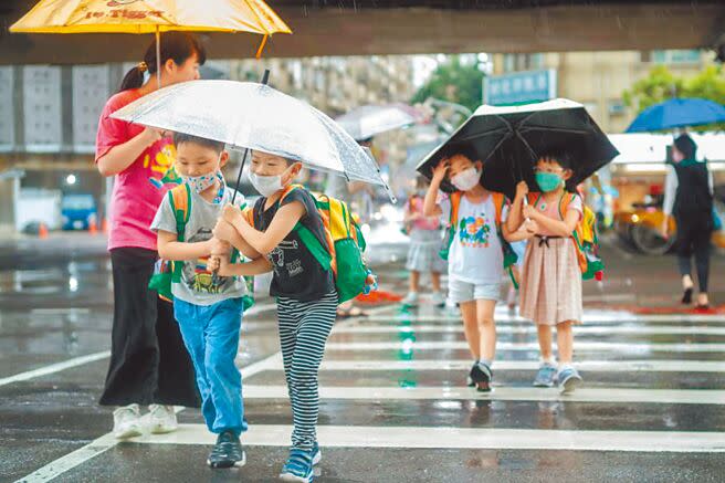 小滿來臨，正式進入梅雨季，小朋友共撐一把傘，互助合作過馬路。（郭吉銓攝）