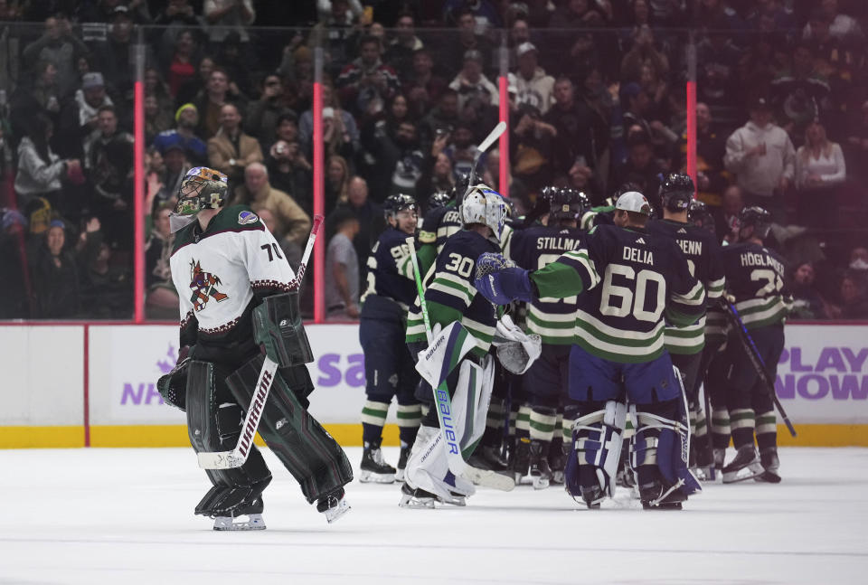 Arizona Coyotes goalie Karel Vejmelka skates off the ice as the Vancouver Canucks celebrate their overtime win in an NHL hockey game Saturday, Dec. 3, 2022, in Vancouver, British Columbia. (Darryl Dyck/The Canadian Press via AP)