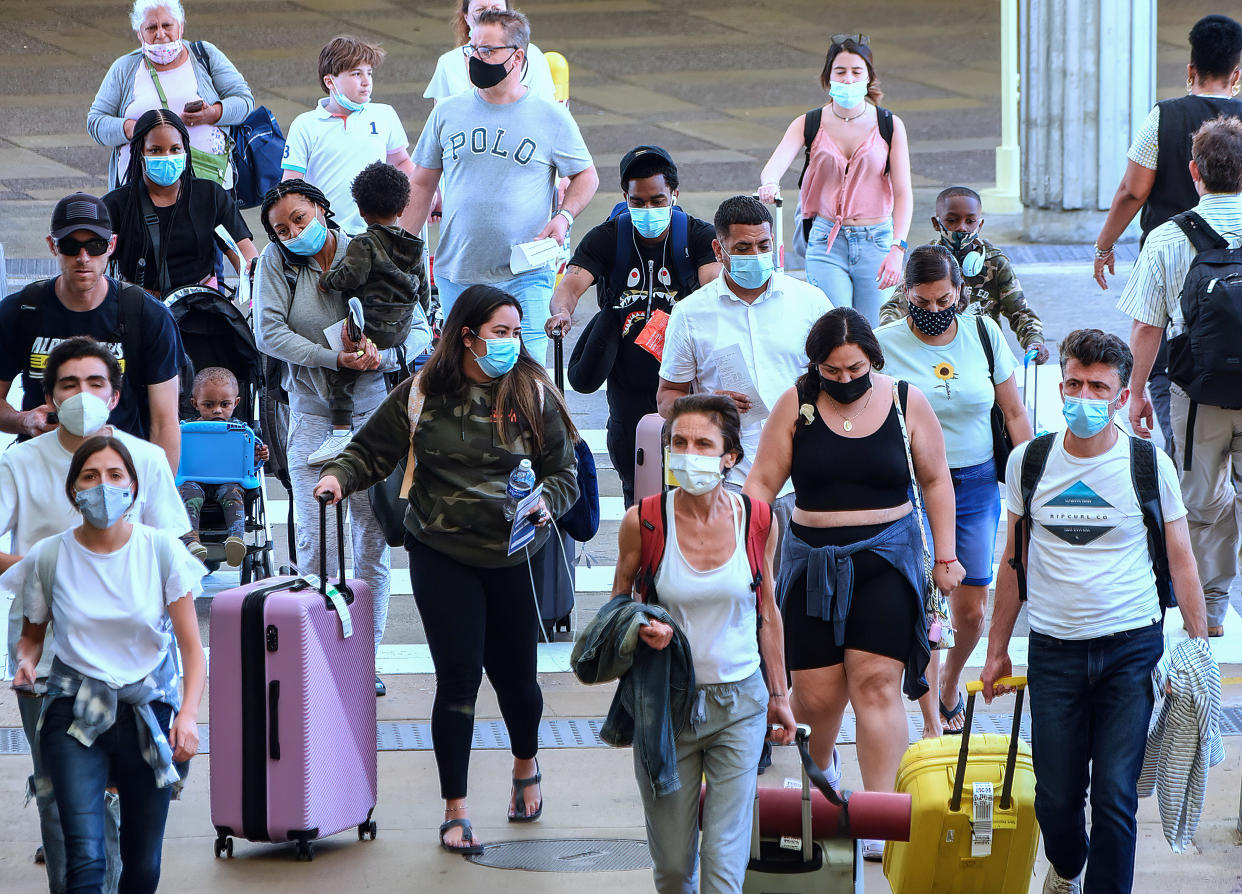 Travelers wearing protective face masks arrive at Orlando International Airport on the Friday before Memorial Day. (Paul Hennessy/SOPA Images/LightRocket via Getty Images)