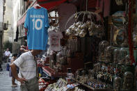 A jersey of soccer legend and former Napoli player Diego Armando Maradona is displayed together with nativity scene statuettes in downtown Naples, Italy, Wednesday, Sept. 18, 2019. Maradona achieved some of his most memorable exploits and in Naples is still revered with god-like status. (AP Photo/Gregorio Borgia)