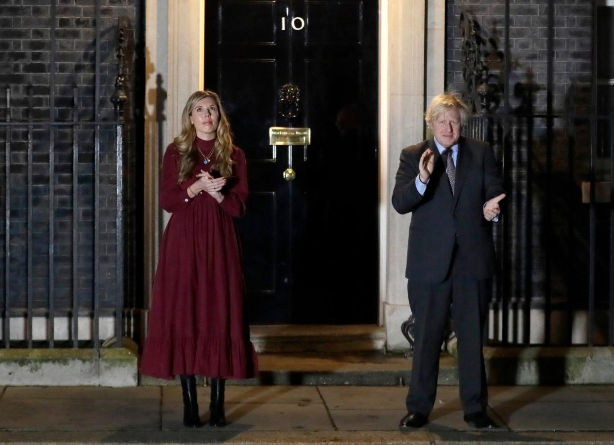 Former Prime Minister Boris Johnson and his partner Carrie Symonds clap on the doorstep of 10 Downing Street to honour Captain Tom Moore after his death (AP)