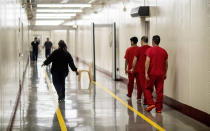 Detainees walk through the halls at the Stewart Detention Center, Friday, Nov. 15, 2019, in Lumpkin, Ga. Immigrants at Stewart are caught in a larger system of immigration courts where crushing caseloads and shifting policies have landed the courts in unprecedented turmoil. (AP Photo/David Goldman)