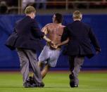 An unidentified fan (C) is arrested after he charged onto the field and dropped his pants in the direction of Atlanta Braves relief pitcher John Rocker in the ninth inning 01 May 2000 in a game with the Los Angeles Dodgers at Dodger Stadium in Los Angeles. The fan ran past extra security to get on the field, and was immediately arrested after delivering his message to the controversial Rocker, who came under fire this past off season for making racist remarks in a press interview. (Photo by Scott Nelson/AFP/Getty Images)