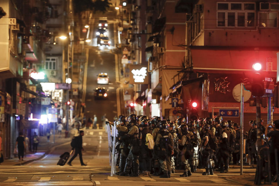 Riot police with shields stand guard as they face with protesters on a street during an anti-extradition ball protest in Hong Kong, Sunday, Aug. 4, 2019. Another police station in Hong Kong became the target of protesters' ire on Sunday as rallies in two different parts of the city converged into one, with participants gearing up for another night of protracted demonstrations. (AP Photo/Vincent Thian)