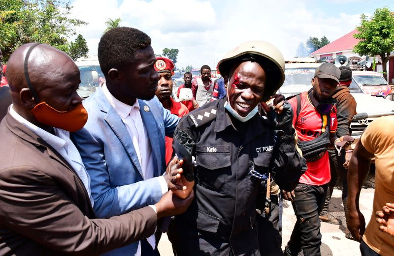 Ugandan pop star and presidential candidate Bobi Wine assists one of his bodyguards who was injured in clashes near Kampala