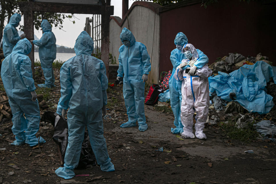 A woman wearing white personal protective equipment, reacts as she takes a glimpse of her husband's body, a victim of COVID-19, in Gauhati, India, Thursday, Sept. 10, 2020. India is now second in the world with the number of reported coronavirus infections with over 5.1 million cases, behind only the United States. Its death toll of only 83,000 in a country of 1.3 billion people, however, is raising questions about the way it counts fatalities from COVID-19. (AP Photo/Anupam Nath)