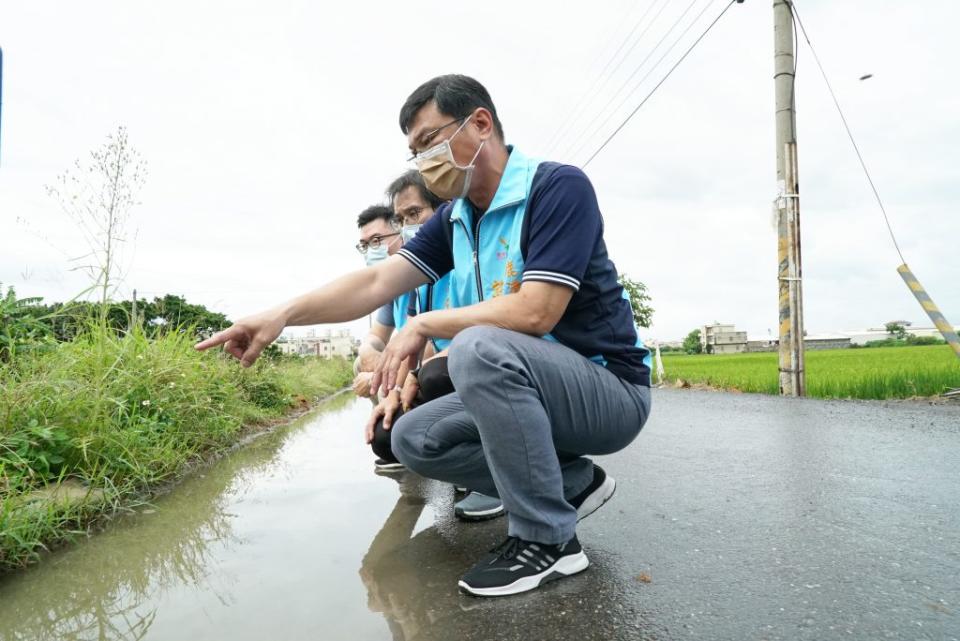 鹿港鎮長許志宏（前）會勘南分圳排水，發現水溝淤塞，水還淹到路面。（記者何國榮攝）