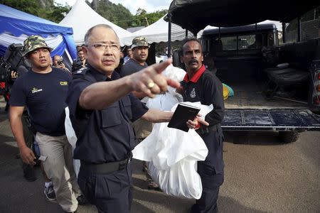 A forensic policeman transports body bags with human remains found at the site of human trafficking camps in the jungle close the Thailand border after bringing them to a police camp near Wang Kelian in northern Malaysia May 25, 2015. REUTERS/Damir Sagolj