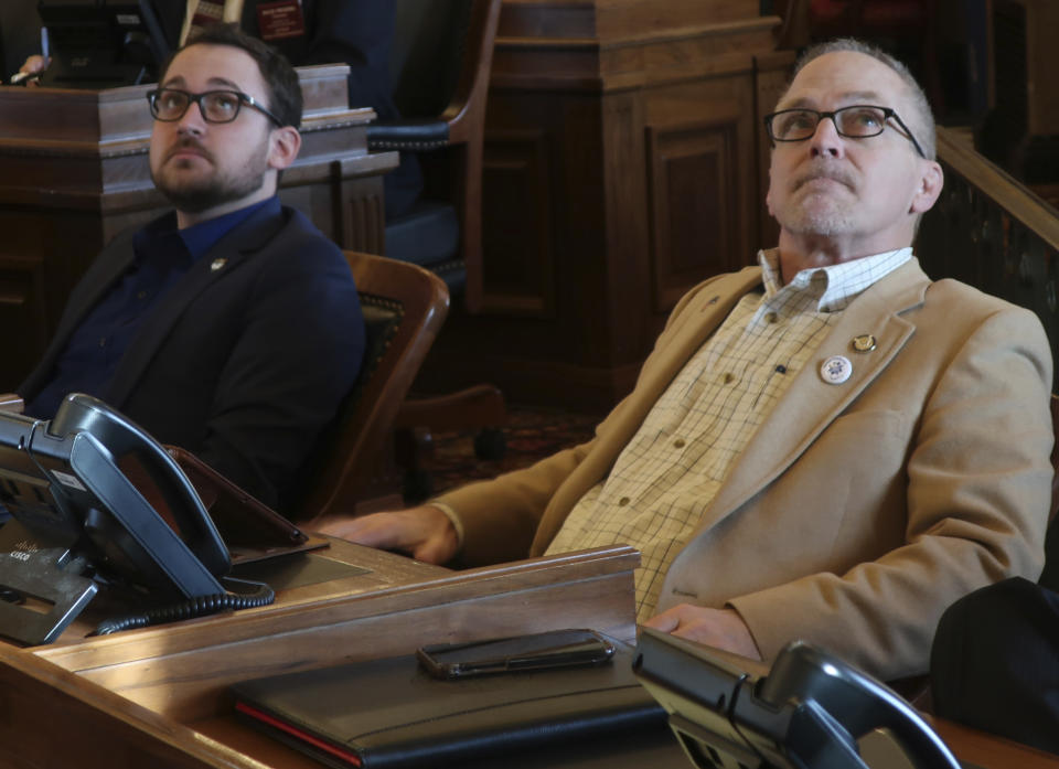 Kansas state Reps. Blake Carpenter, left, R-Derby, and Bradley Ralph, R-Dodge City, watch an electronic tally board as the House approves an anti-abortion bill that they favor, Friday, April 5, 2019, at the Statehouse in Topeka, Kansas. The bill would require abortion providers to tell patients that medication abortions can be reversed after they take the first of two pills. (AP Photo/John Hanna)
