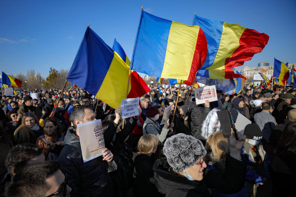 Anti-vaccination protesters waving national flags during a rally outside the parliament building in Bucharest, Romania, Sunday, March 7, 2021. Some thousands of anti-vaccination protestors from across Romania converged outside the parliament building protesting against government pandemic control measures as authorities announced new restrictions amid a rise of COVID-19 infections. (AP Photo/Vadim Ghirda)
