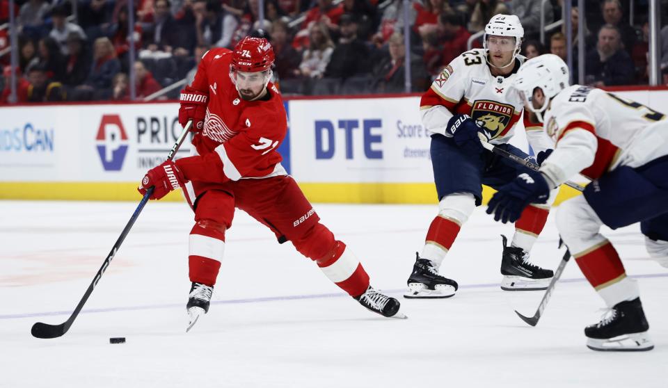 Detroit Red Wings center Dylan Larkin (71) passes the puck against Florida Panthers center Carter Verhaeghe (23) and Florida Panthers defenseman Oliver Ekman-Larsson, right, during the first period of an NHL hockey game Saturday, March 2, 2024, in Detroit. (AP Photo/Duane Burleson)