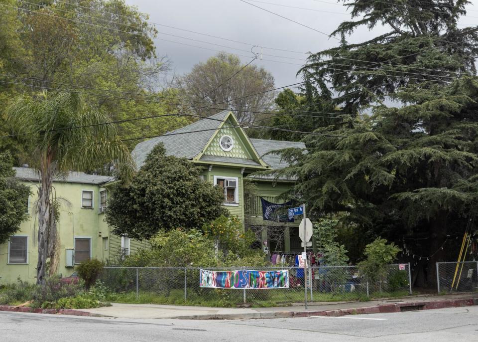 A pale green Victorian home seen from a distance.