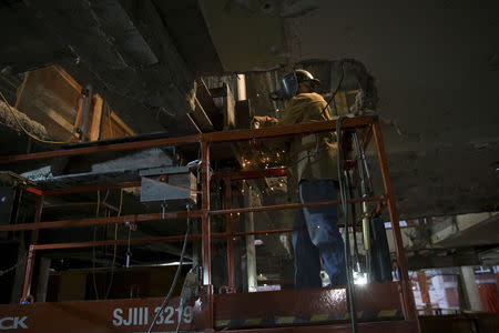 A worker works on a beam inside 390 Madison Avenue, an office building in midtown Manhattan in New York that is undergoing a complete re-construction November 10, 2015. REUTERS/Mike Segar