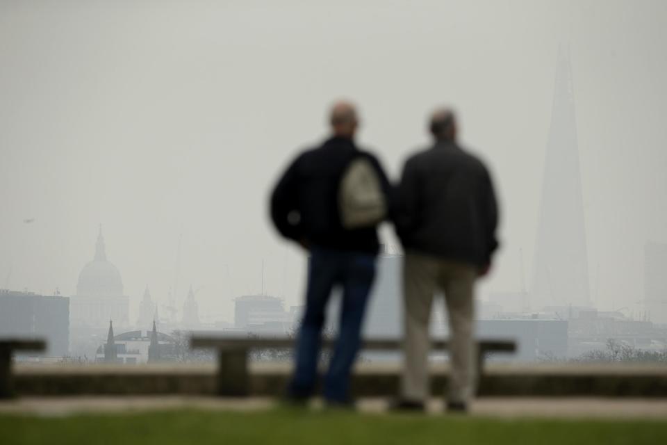 Men look out at the view from Primrose Hill in London, as St Paul's Cathedral, at left, and the Shard skyscraper, the tallest building in the UK, stand shrouded in smog, Thursday, April 3, 2014. European pollution and dust swirling in from the Sahara created a "perfect storm" of smog in Britain on Wednesday, prompting authorities to warn people with heart or lung conditions to cut down on tough physical exercise outdoors. Air pollution in some areas reached the top rung on its 10-point scale, the environment department said. (AP Photo/Matt Dunham)