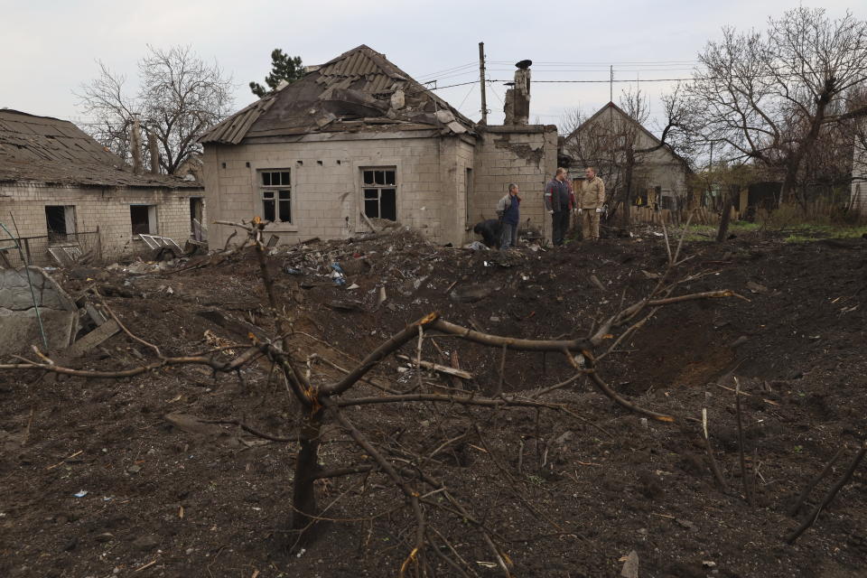 Local residents stand near a crater left by a Russian missile in Zaporizhzhia , Ukraine, Sunday, April 9, 2023. An 11-year old girl and her father were killed in the rocket attack in Zaporizhzhia. (AP Photo/Kateryna Klochko)