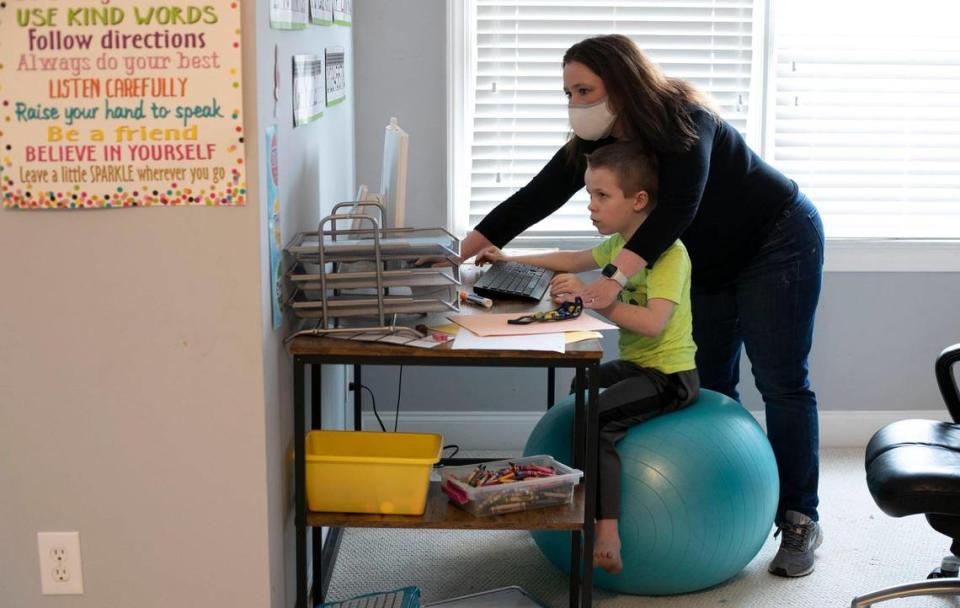 Lynda Manus works with her seven-year-old son Bryce Manus, a first-grader, to keep him focused on his virtual classes on Friday, March 26, 2021in Cary, N.C.