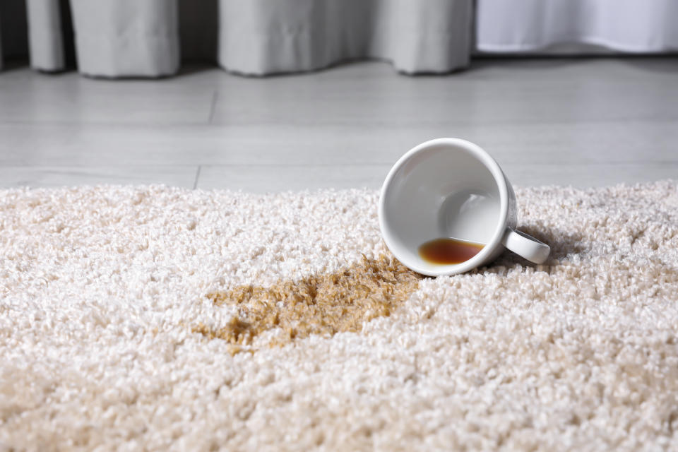 Overturned cup and spilled tea or coffee on beige carpet, closeup