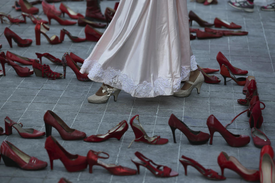 An actress walks near a line of red shoes representing murdered women, as part of a performance during the International Women's Day strike "A Day Without Women" in Mexico City, Monday, March 9, 2020. Thousands of women across Mexico went on strike after an unprecedented number of girls and women hit the streets to protest rampant gender violence on International Women's Day. (AP Photo/Fernando Llano)