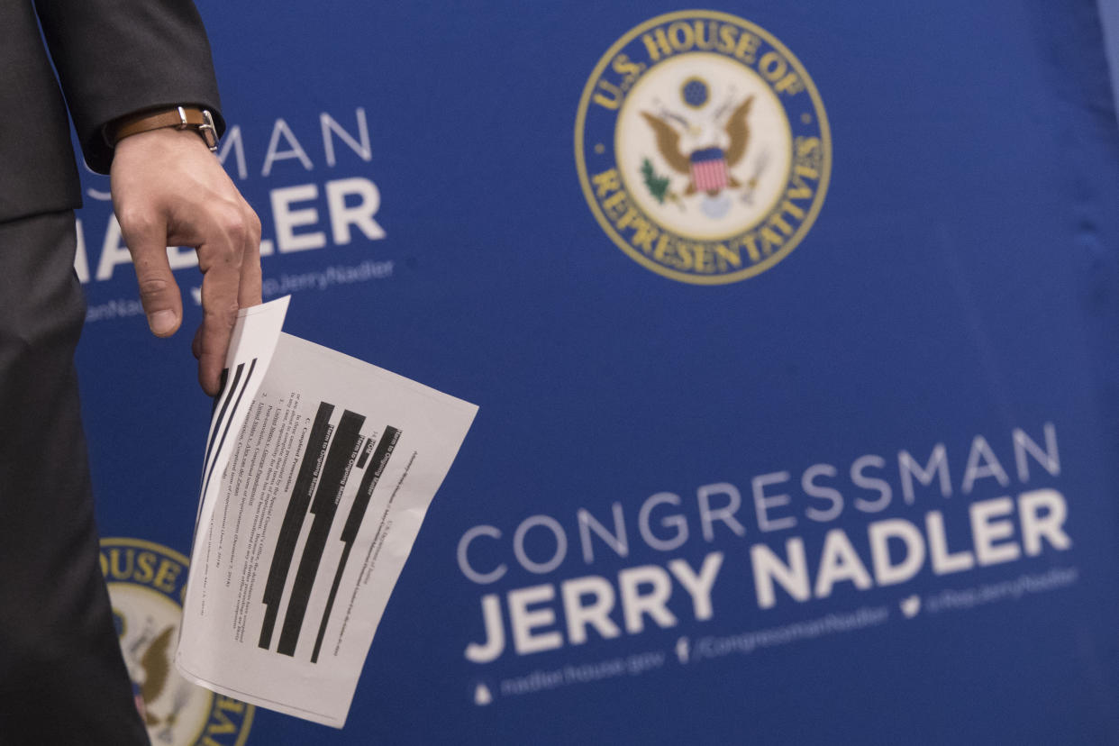 An aide to U.S. Rep. Jerrold Nadler, D-N.Y., chair of the House Judiciary Committee, holds a page from the redacted Robert Mueller report ahead of a news conference, Thursday, April 18, 2019, in New York. (AP Photo/Mary Altaffer)