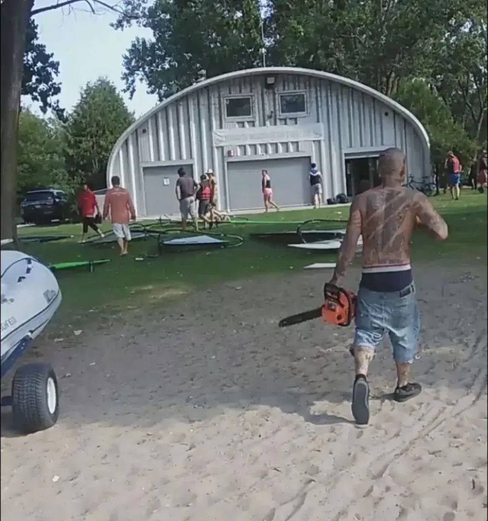 A man is seen carrying a chainsaw approaching pedestrians. Two men were arrested near Cherry Beach on Aug 9. following reports of a large fight breaking out. (David Sullivan/Facebook)