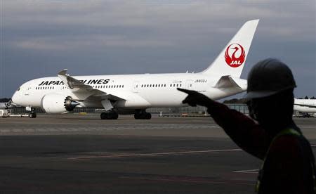 A staff of Japan Airlines' (JAL) walks past one of the company's Boeing Co's 787 Dreamliner plane at Narita international airport in Narita, east of Tokyo, November 11, 2013. REUTERS/Toru Hanai