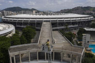 Con el estadio Maracaná de fondo, el bombero Elielson Silva toca su trompeta desde lo alto de la escalera desplegada de su camión en Río de Janeiro el 5 de abril del 2020. (AP Photo/Leo Correa)