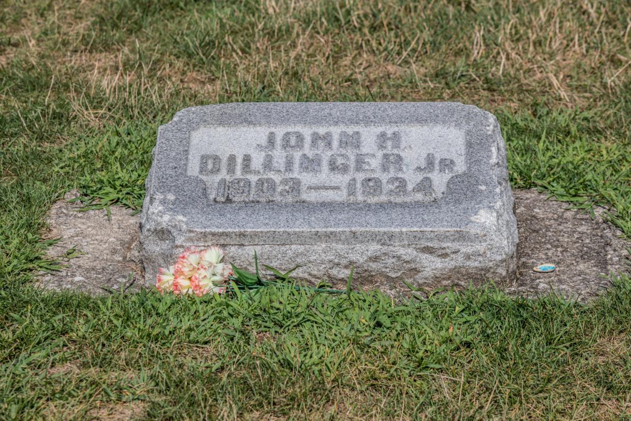 The grave of  John Dillinger Jr., 1909-1934, sits inside the walls of Crown Hill Cemetery in Indianapolis on Tuesday, July 30, 2019. Dillinger's smaller headstone sits in the family plot marked by a larger headstone. Small chunks of the stone, which may have been replaced once, have been chipped off by visitors over the years.