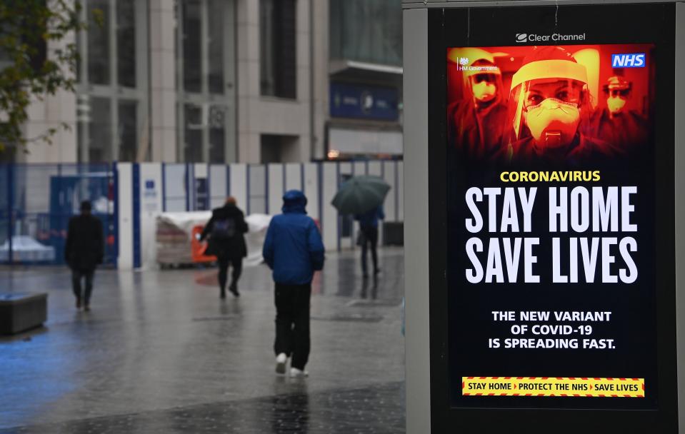 Pedestrians walk past COVID-19 information boards in Liverpool, on January 13, 2021, as non-essential retailers keep their shops closed, due to England's third lockdown. - Britain's interior minister on Tuesday warned that anyone flouting coronavirus lockdown rules would face action from the police, as the government vowed to step up enforcement measures to cut surging infection rates that risk overwhelming health services. (Photo by Paul ELLIS / AFP) (Photo by PAUL ELLIS/AFP via Getty Images)