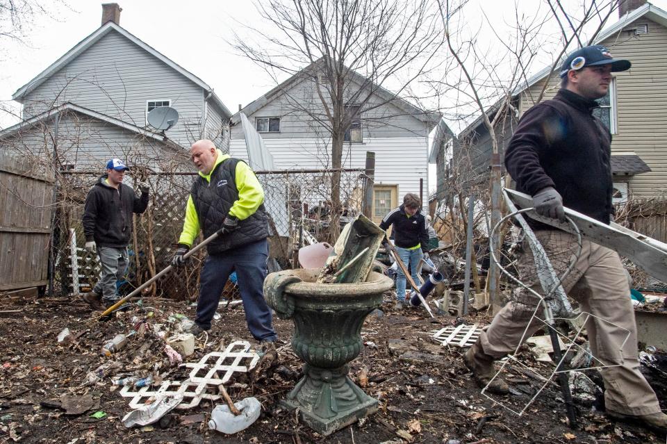 Parks workers with the city of Erie clear debris from the backyard of a house at 1618 Chestnut St., in background, on Monday, April 11, 2022. The crews also used garbage trucks and a front-end loader with a claw attachment to get rid of junk that had become such a hazard that the city got a court order to remove it.