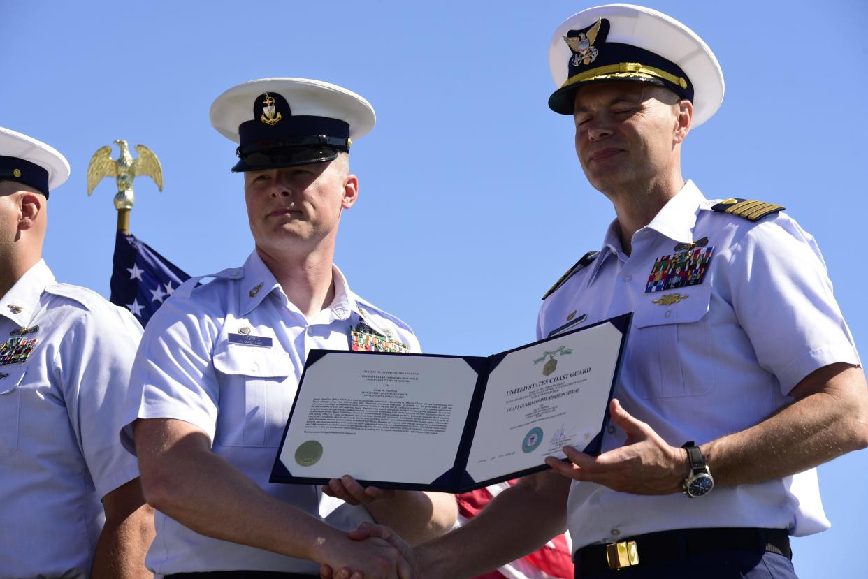 Kyle Thomas (left), is handed an award on behalf of Commander of Coast Guard Sector Detroit Capt. Brad Kelly during the change of command ceremony on Friday, June 17, 2022, at the U.S. Coast Guard Station in Port Huron.